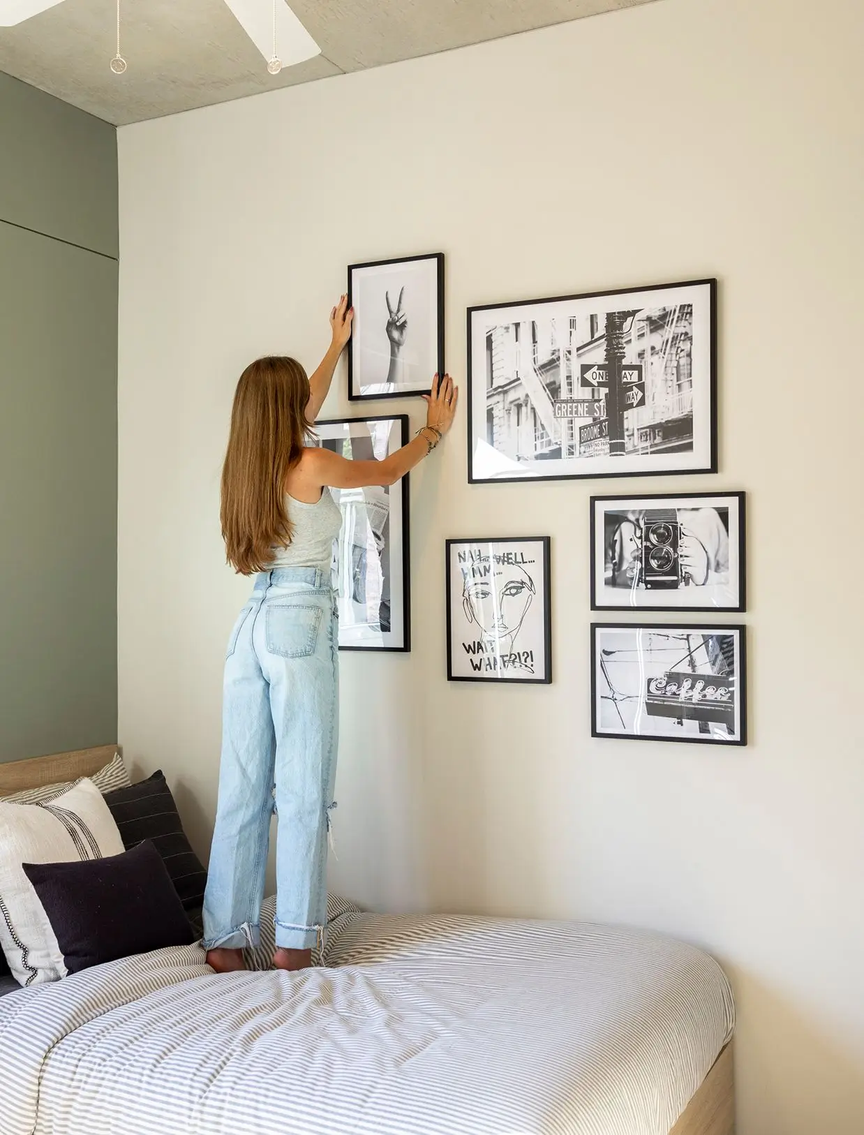 Girl decorating apartment with framed pictures